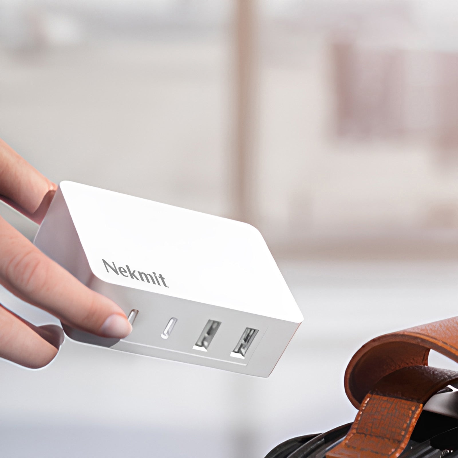 Nekmit USB hub with a hand holding it on a blurred background