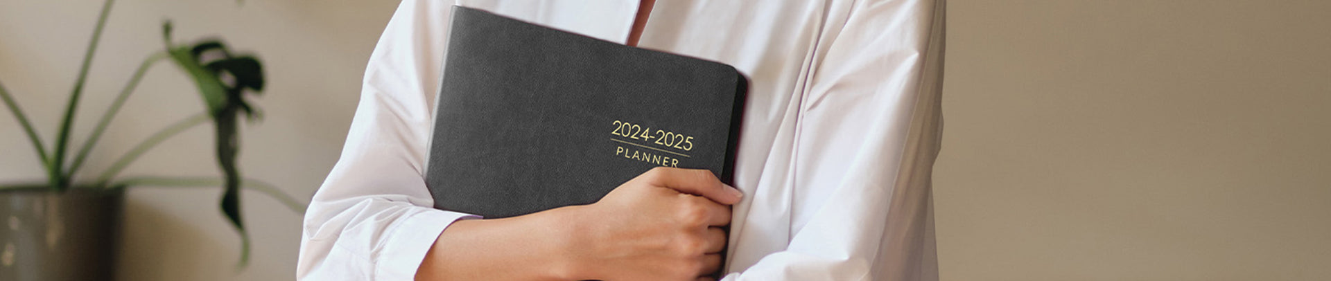 Person holding a planner with '2024-2025' text, blurred background