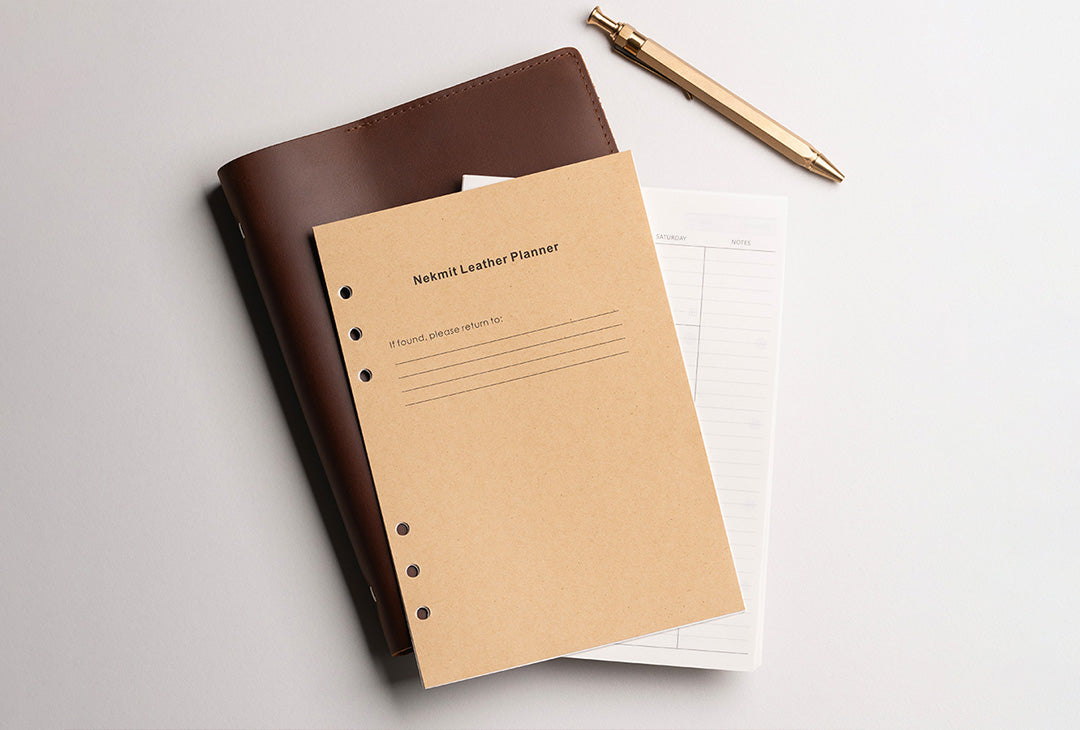 Brown leather planner and beige notebook on a light gray background