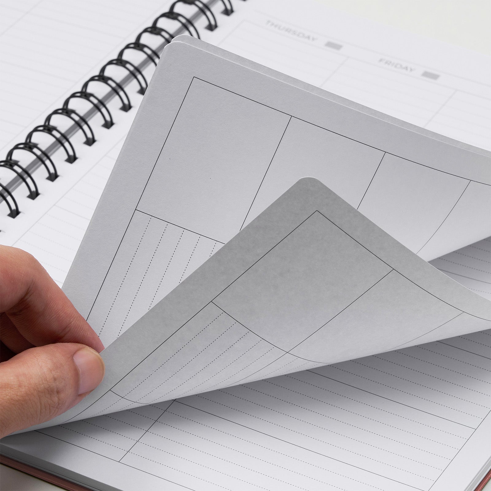 Person holding a sheet of lined paper over an open notebook