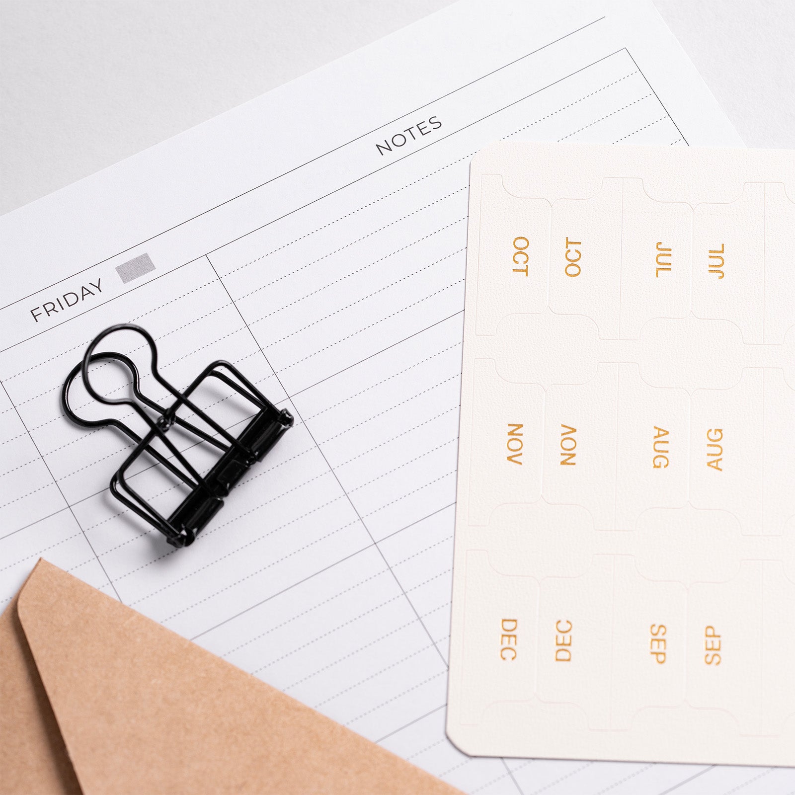 Black binder clip on a planner with a calendar card in the background