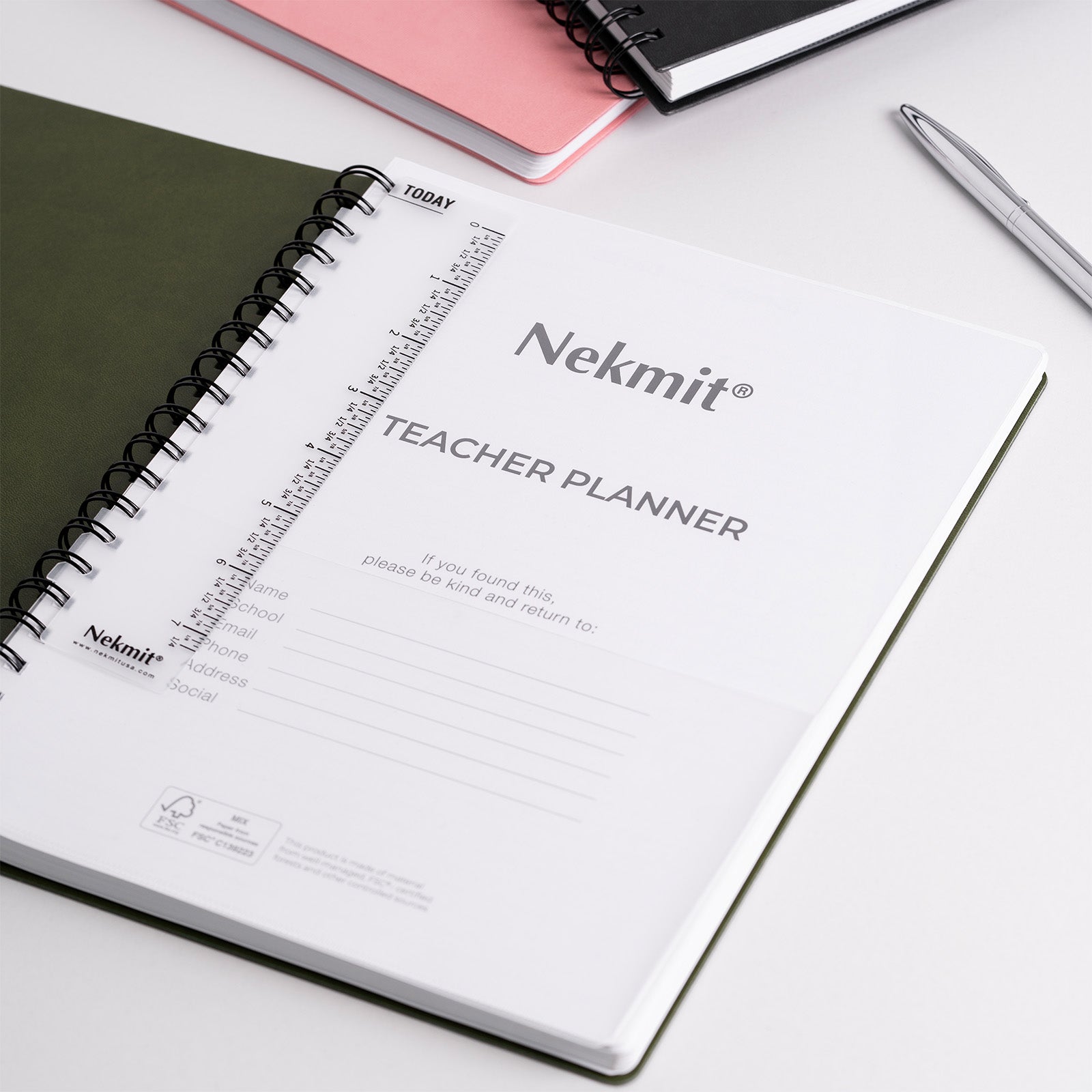Nekmit teacher planner on a white surface with a pen and pink notebook.