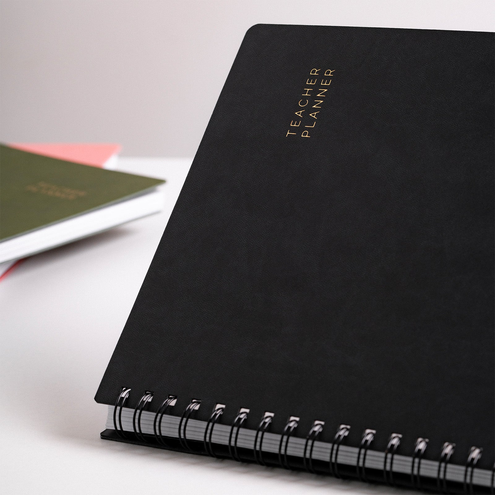 Black planner with 'Teacher Planner' embossed on it, lying on a white surface.
