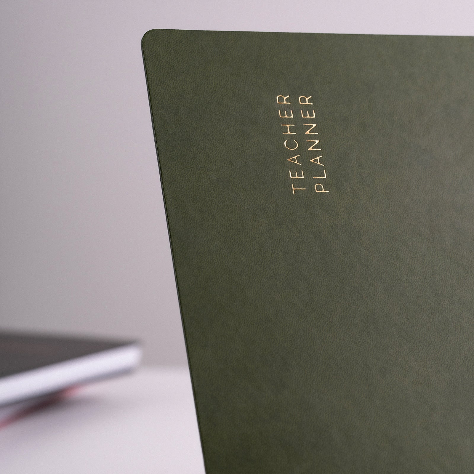 Green planner with 'Teacher Planner' text on a light background