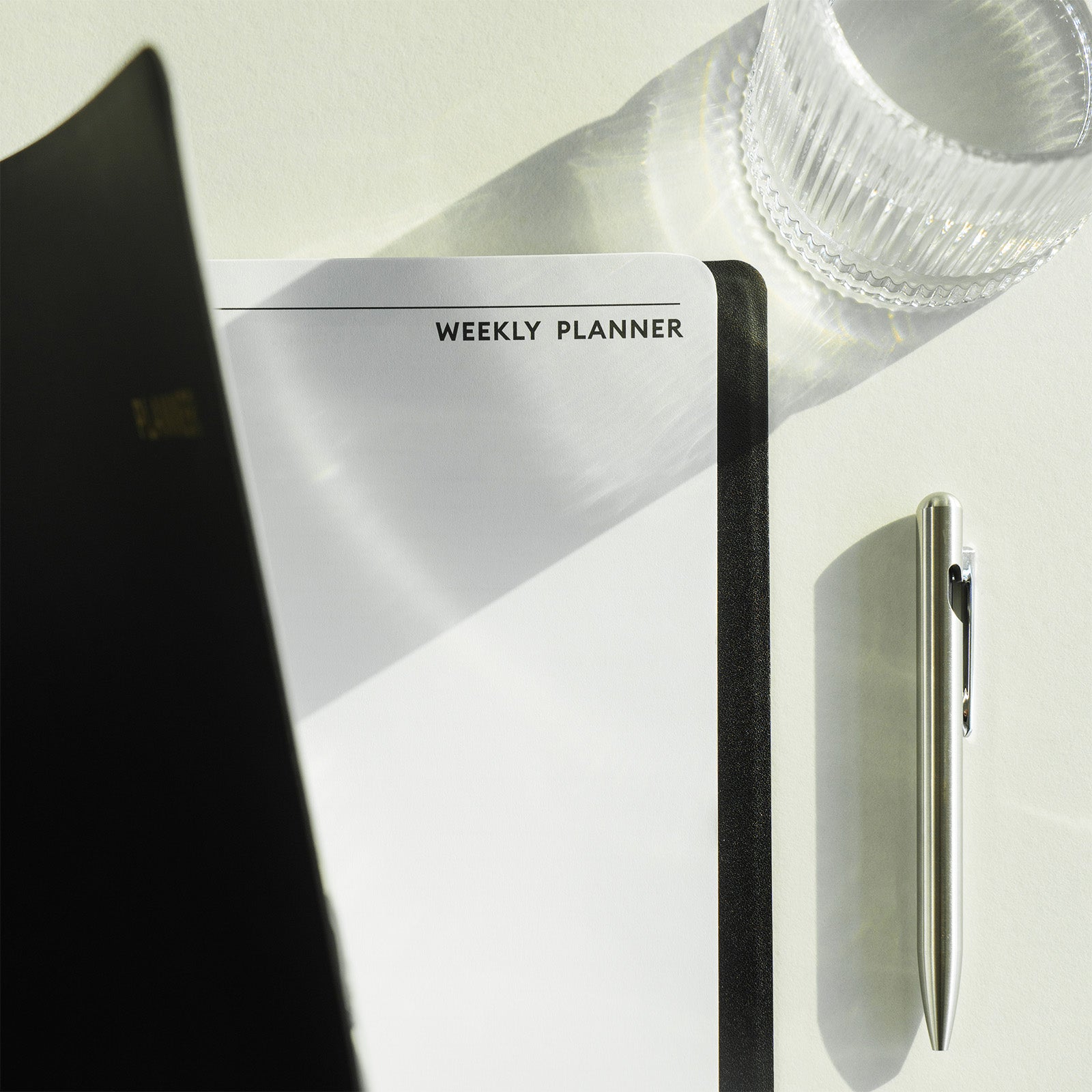 Weekly planner with a pen on a white surface