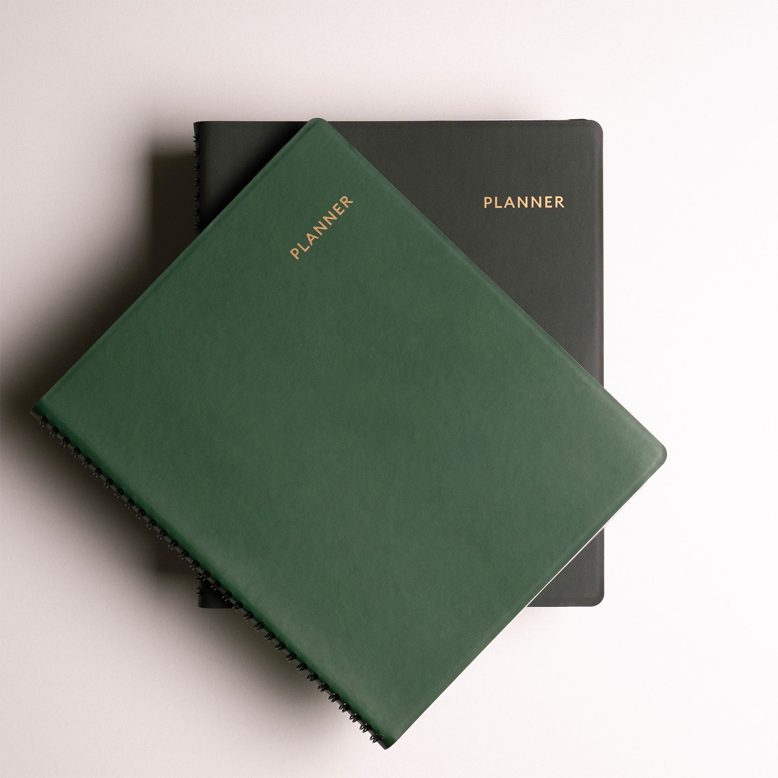 Two planners, one green and one black, on a light background