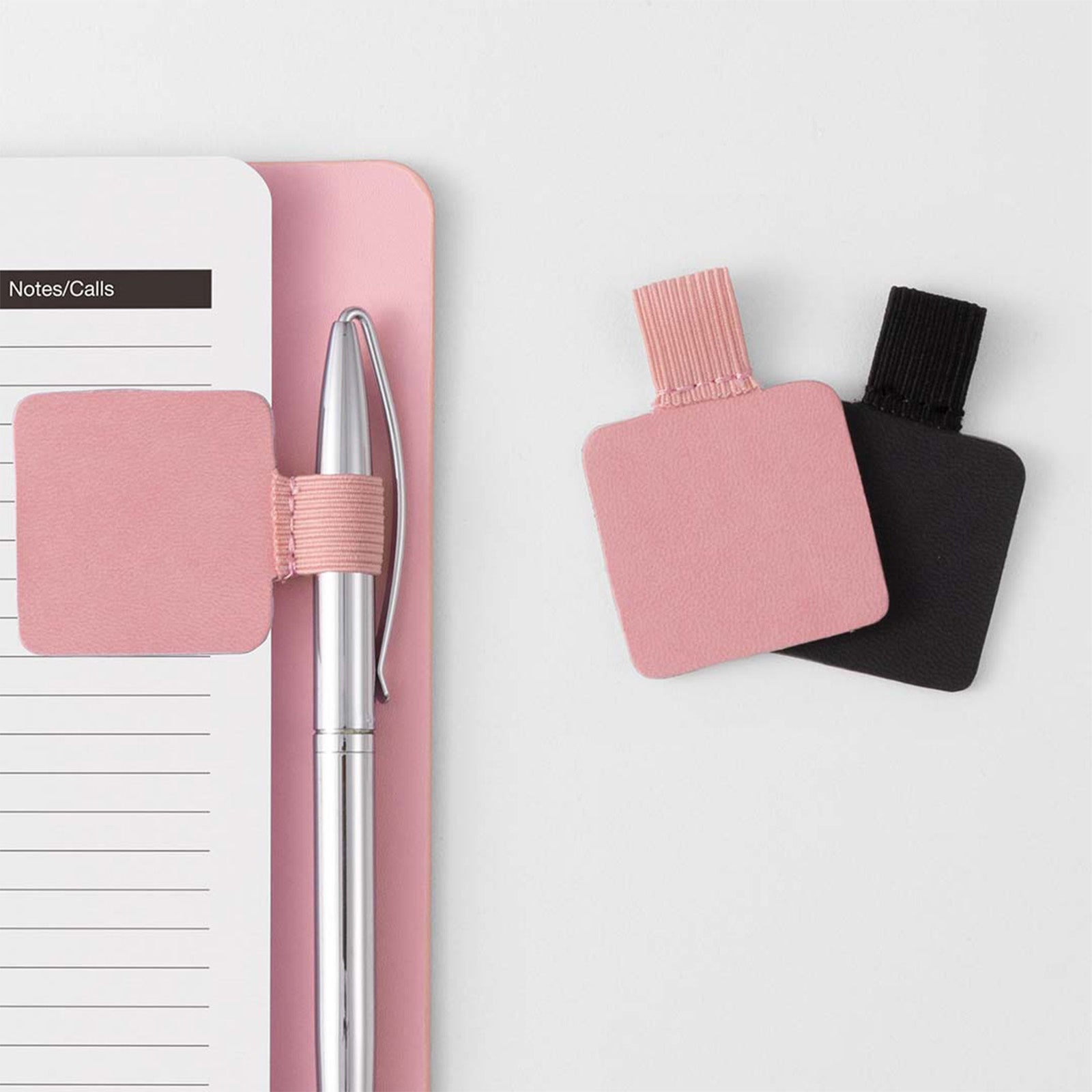 Pink pen with a notebook and two small bottles on a light gray background