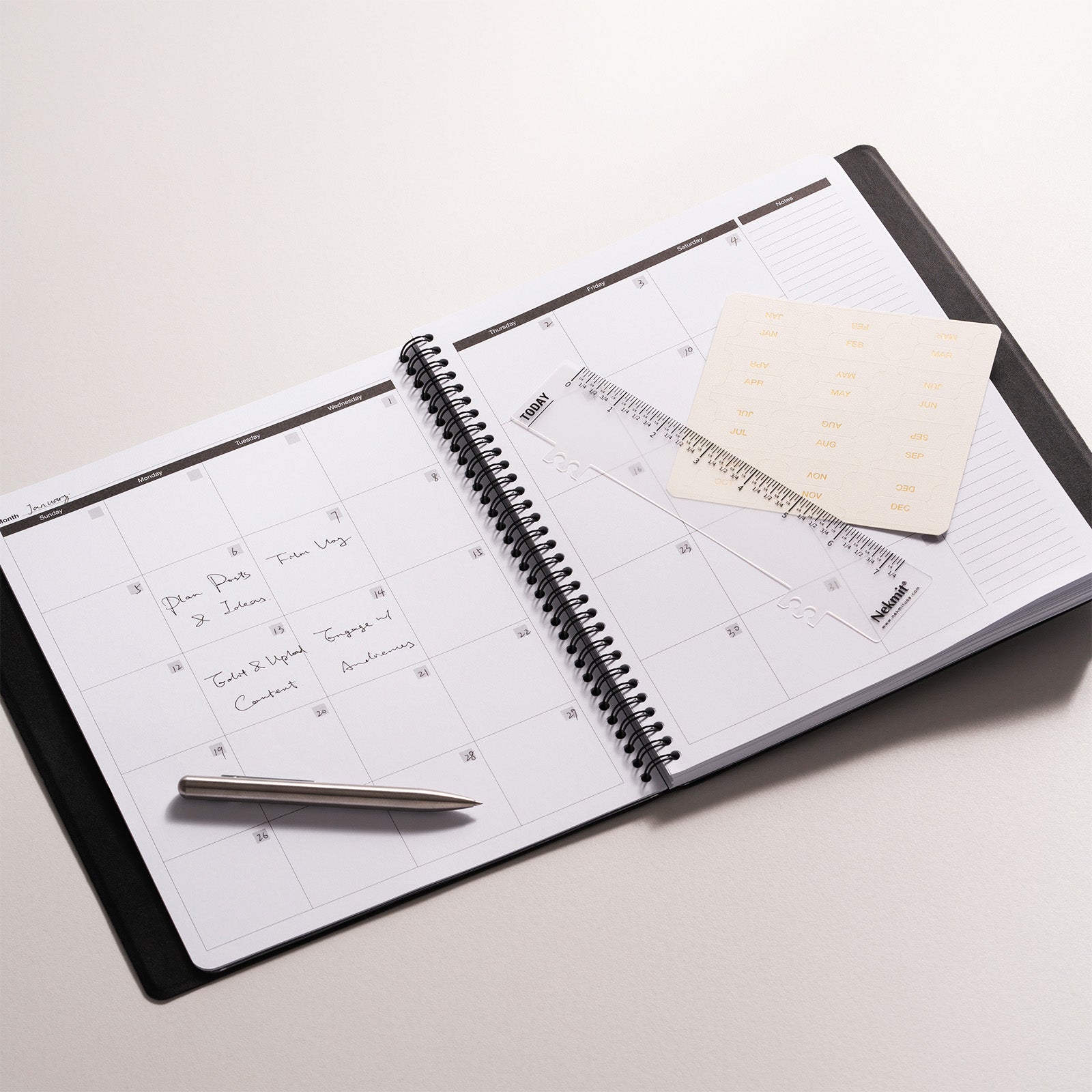 Open planner with pen, ruler, and sticky notes on a light surface