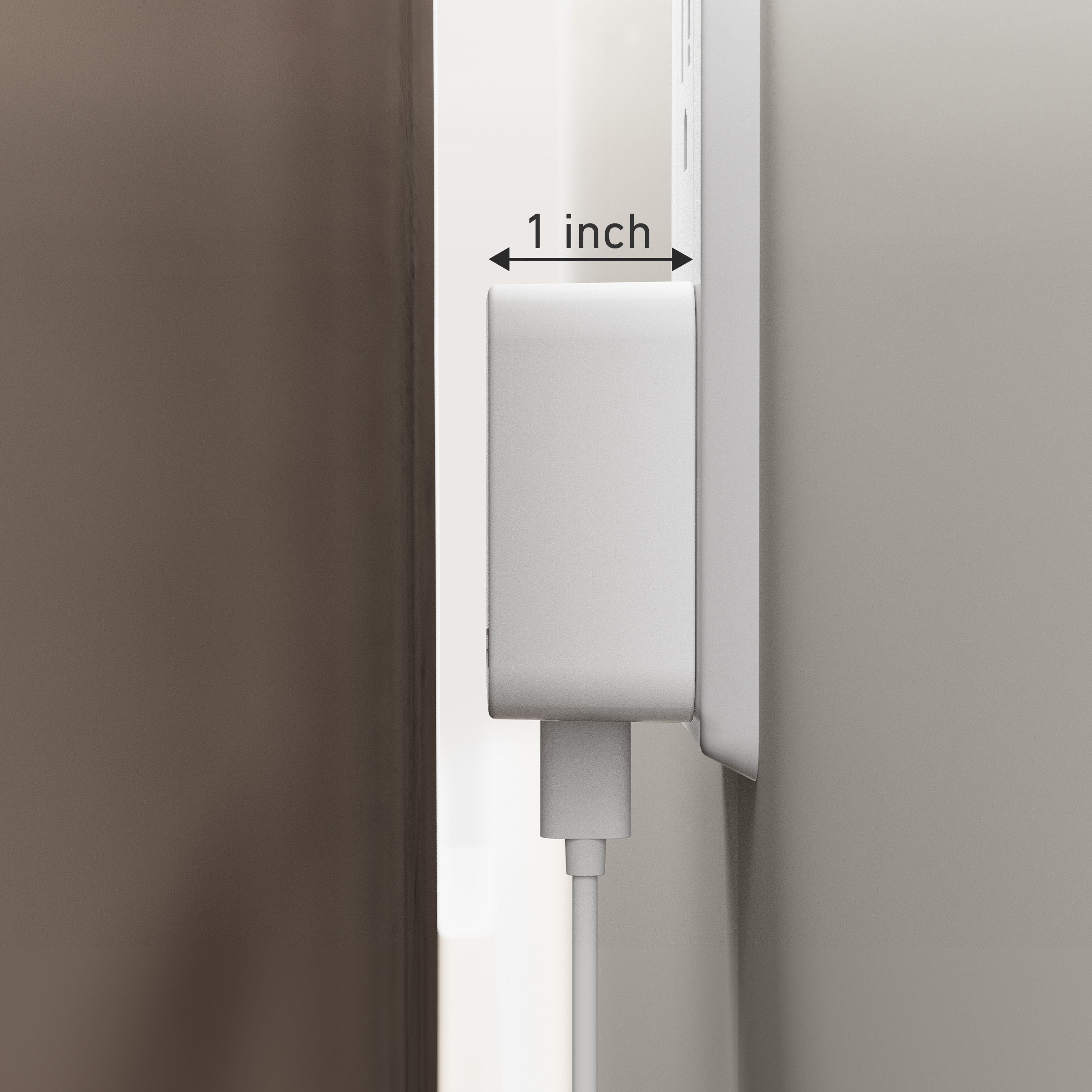 White wall-mounted device with a cable, showing a measurement of 1 inch on a brown background.