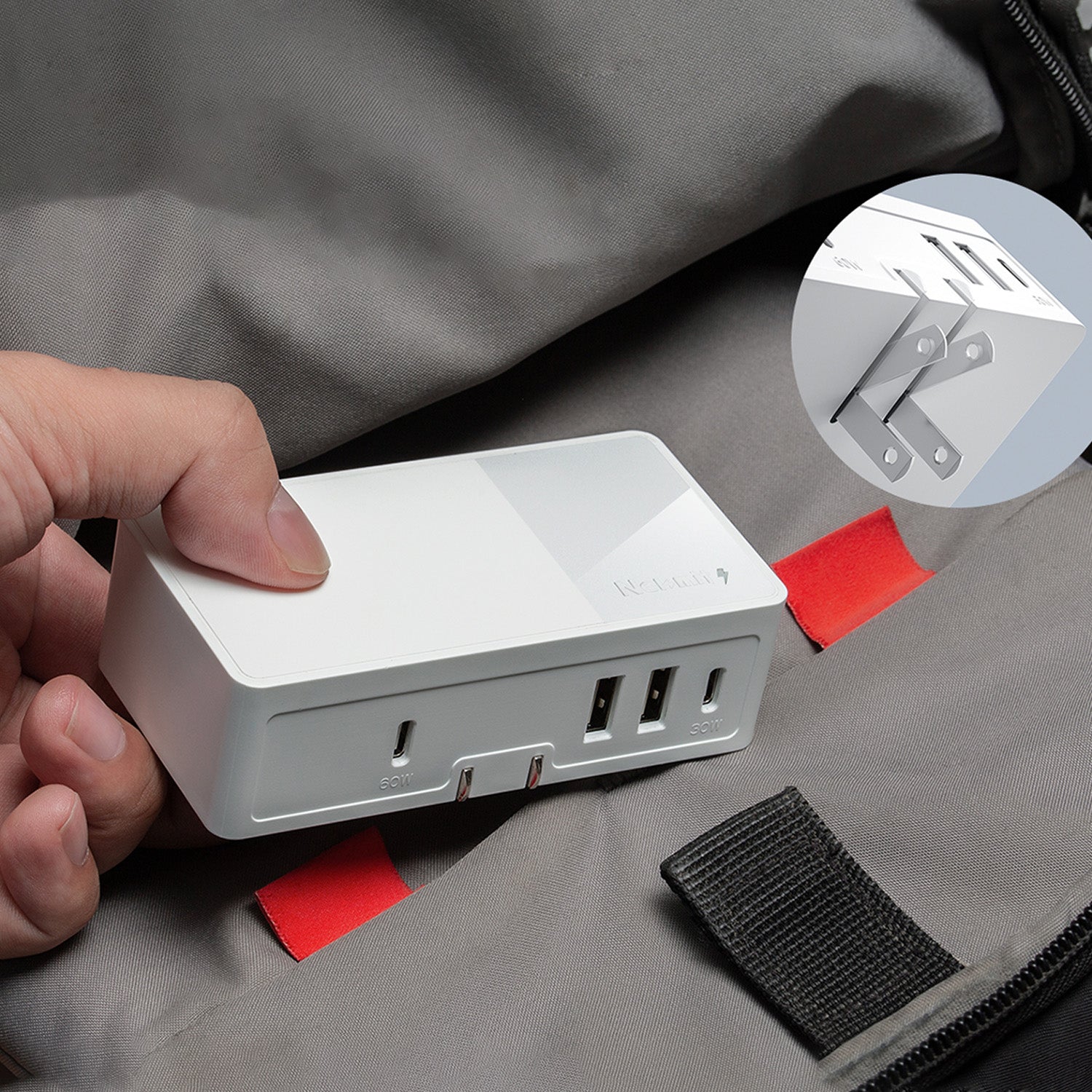 Person holding a white power adapter with multiple ports on a gray surface