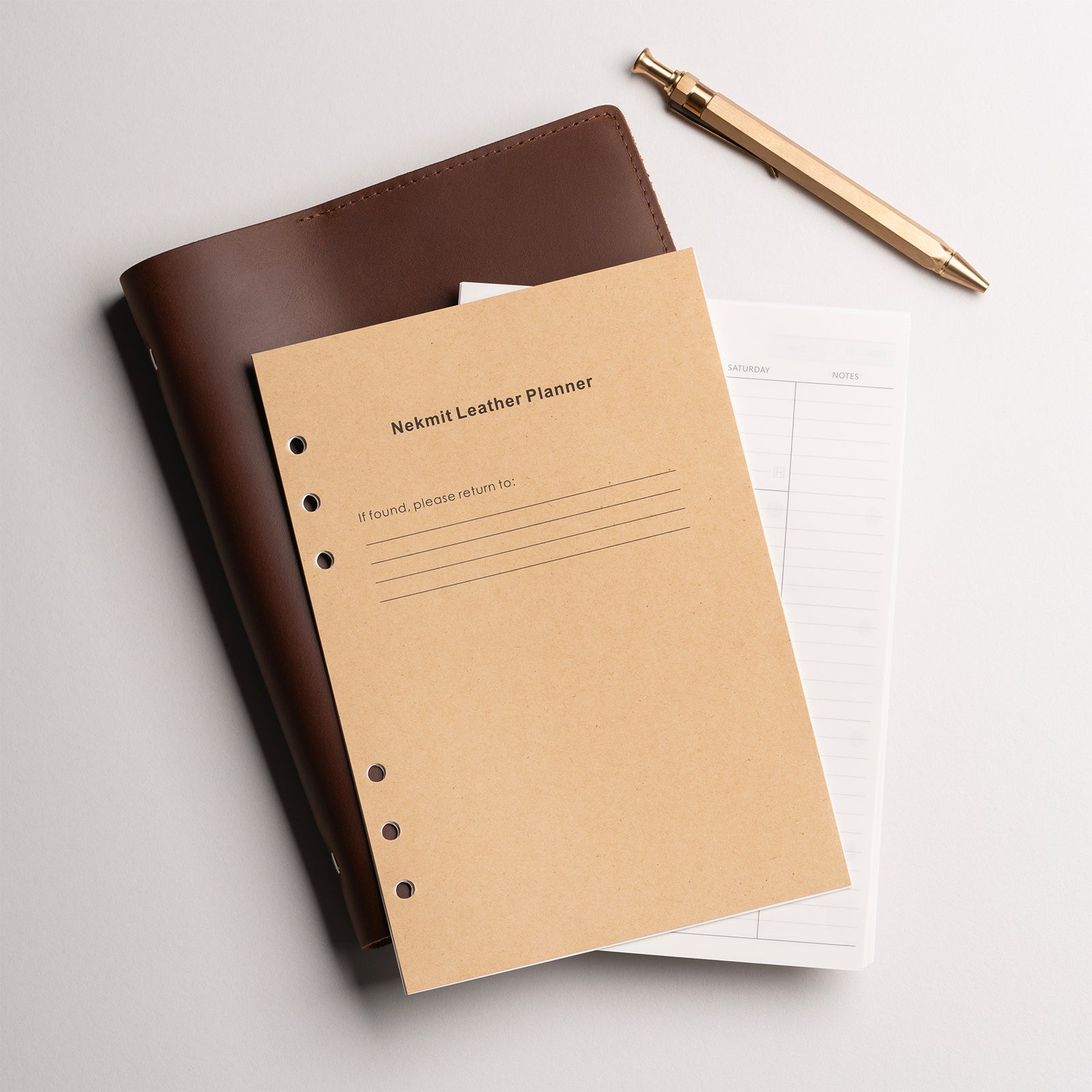 Brown leather planner and beige notebook with a gold pen on a light gray background