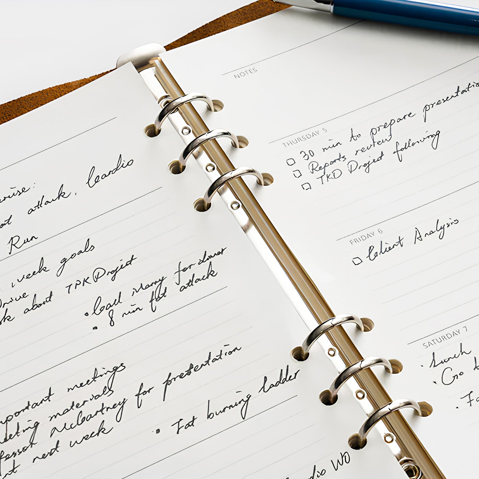 Open planner with handwritten notes and a pen on top