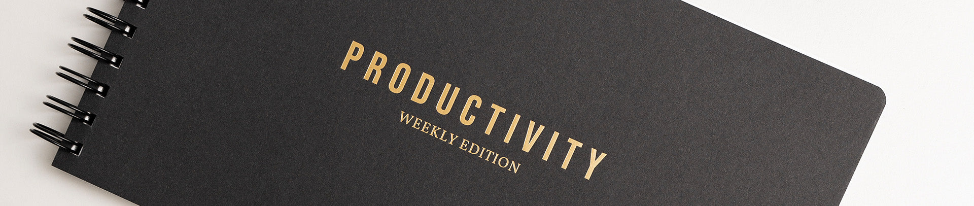 Black notebook with 'Productivity Weekly Edition' text on a white background