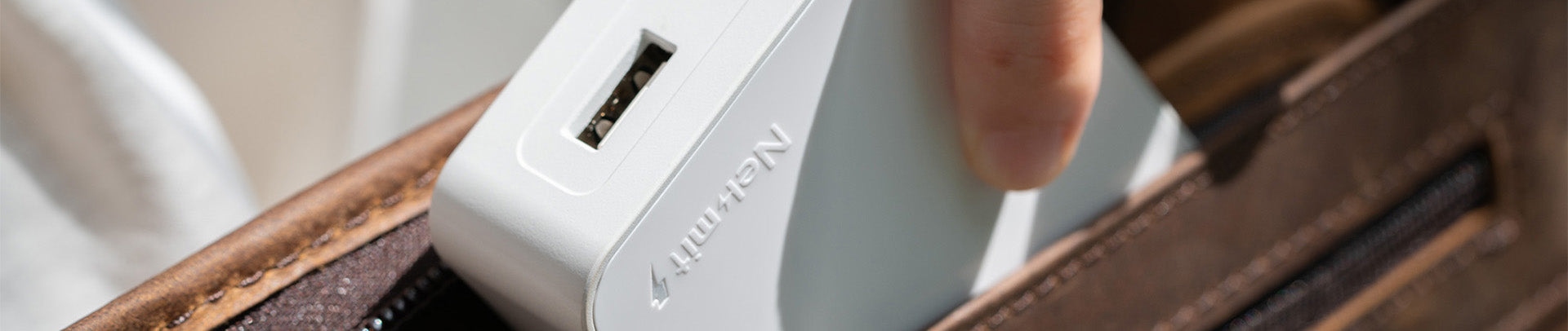 Close-up of a person using a white electronic device with 'Caterpillar' branding on a wooden surface.