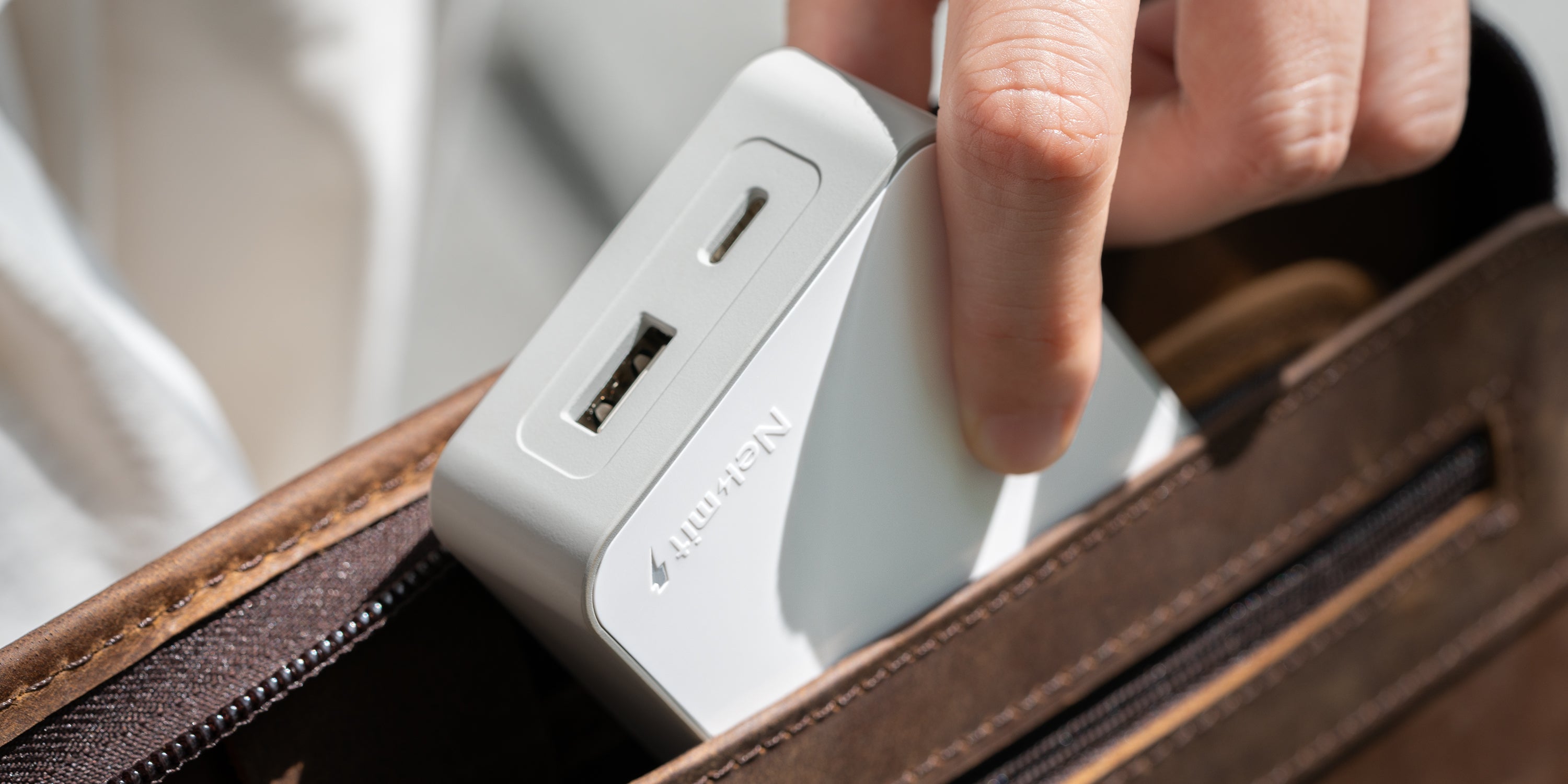 Person inserting a power adapter into a suitcase