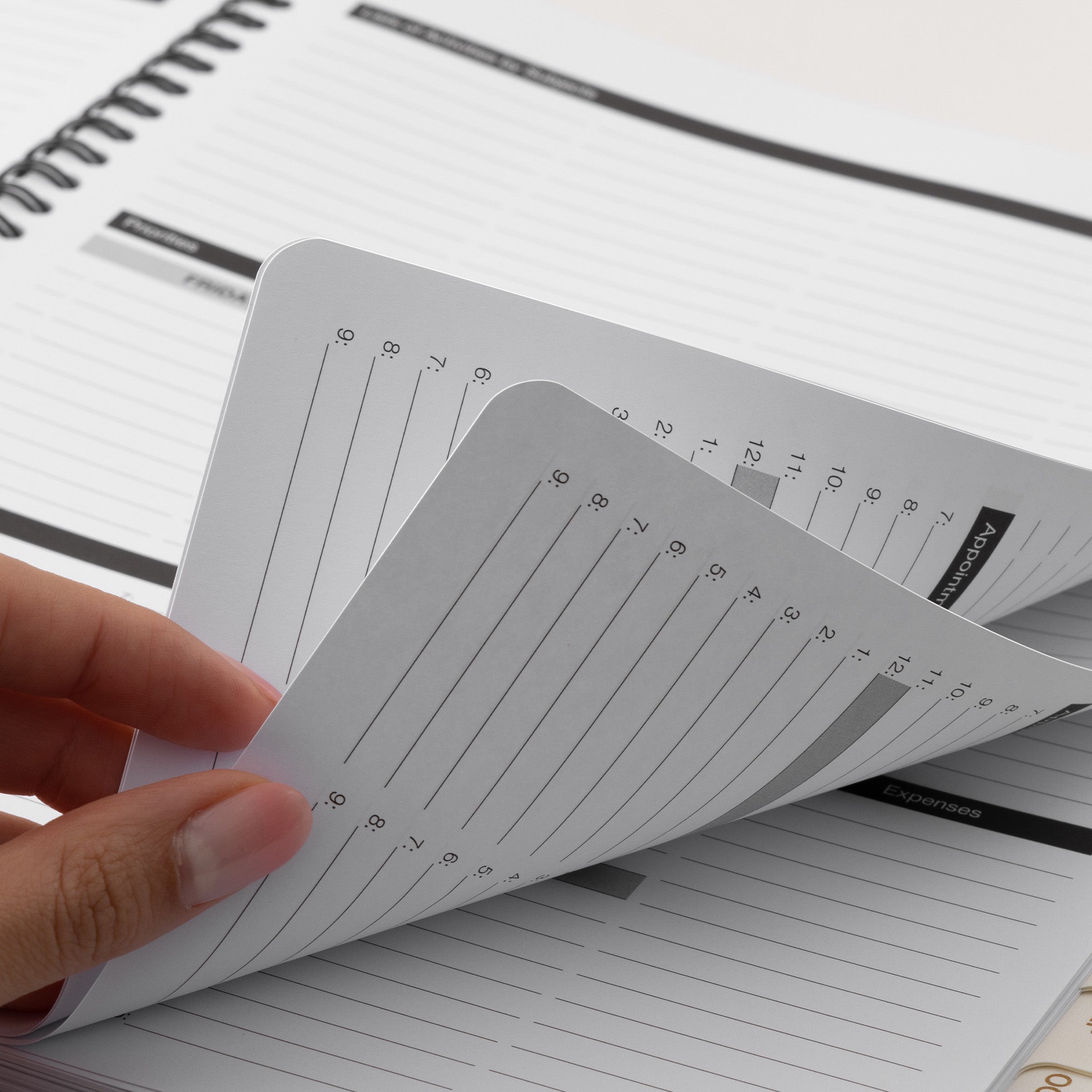 Hand holding a small notebook with lined pages on a larger notebook background